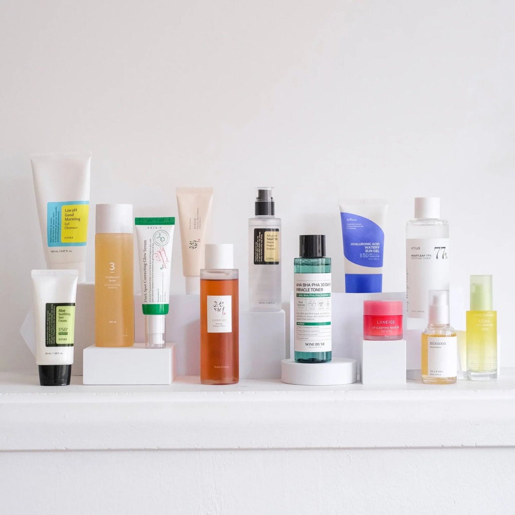 Row of skincare products on a white shelf with a white background