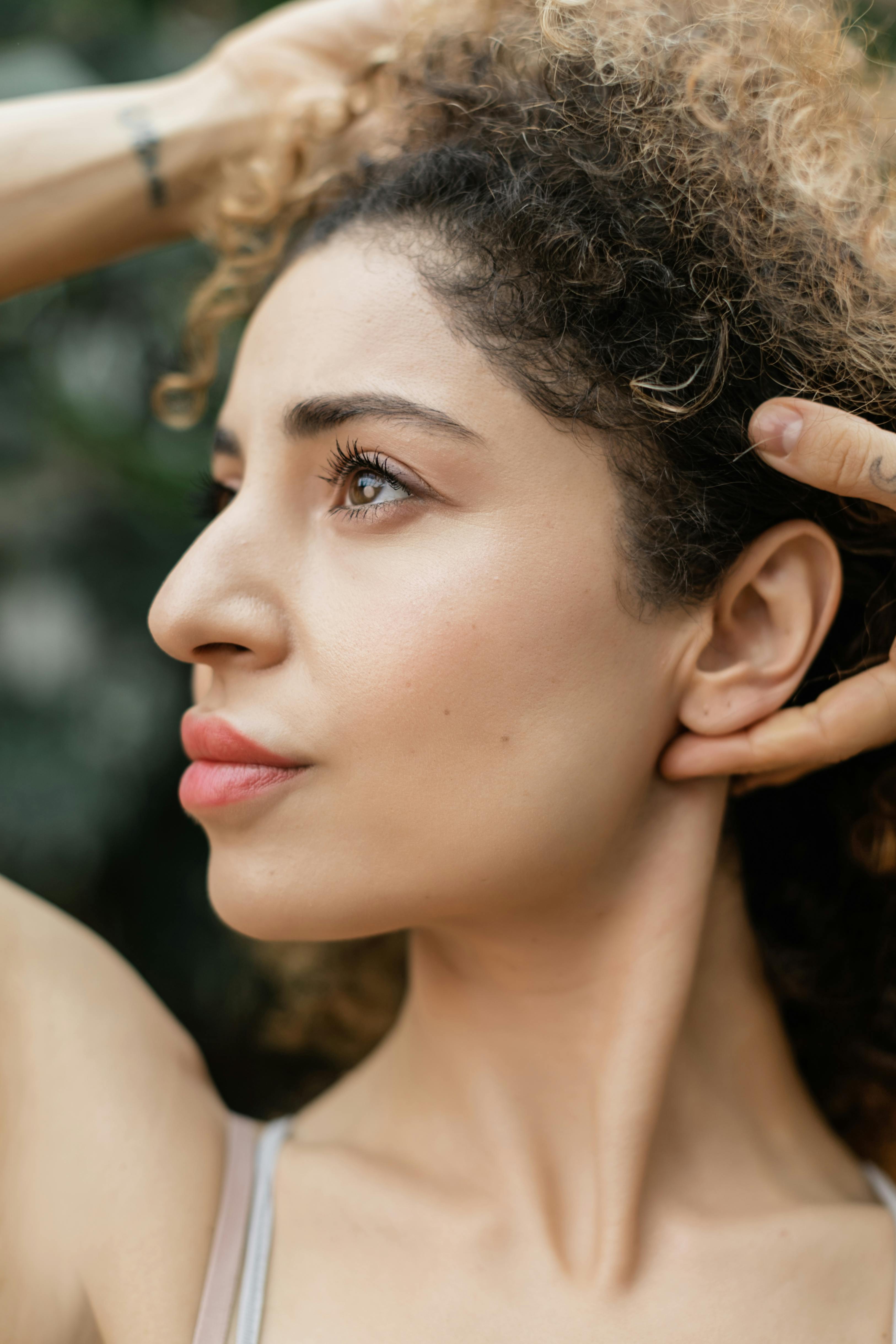 Close-up of a woman with curly hair being adjusted outdoors
